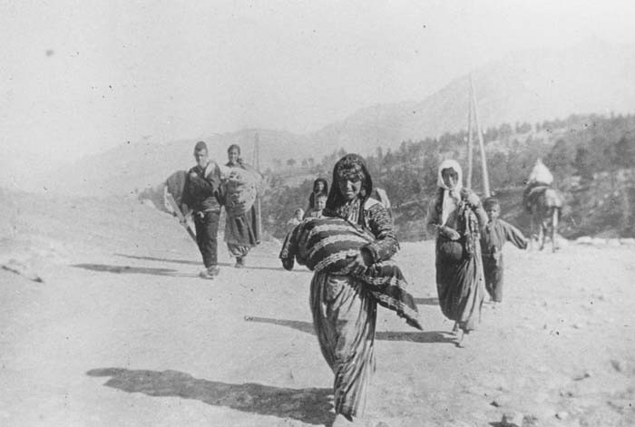 A small group of Armenian deportees walking through the Taurus Mountain region, carrying bundles.